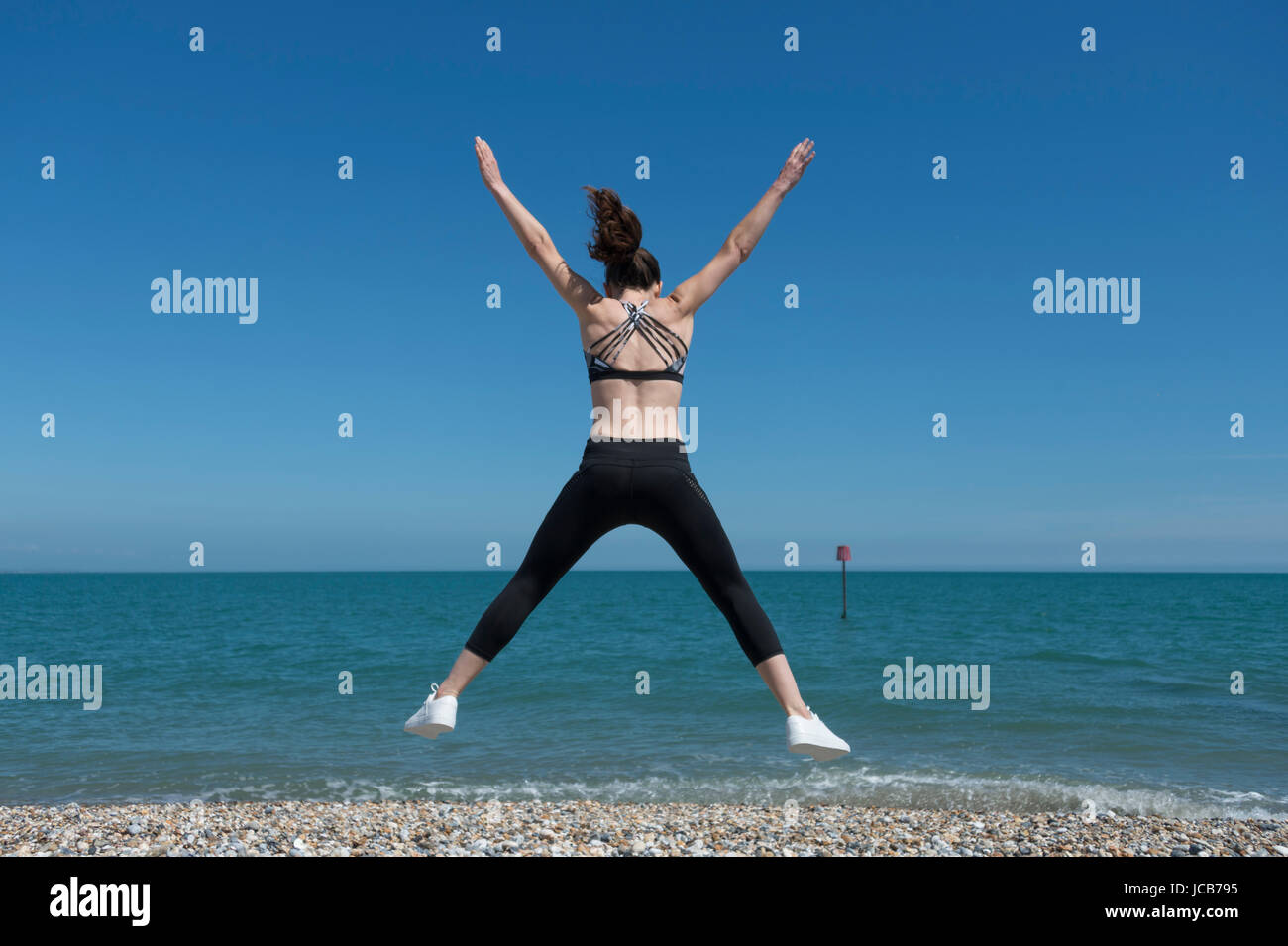 Donna facendo un salto a stella sulla spiaggia Foto Stock