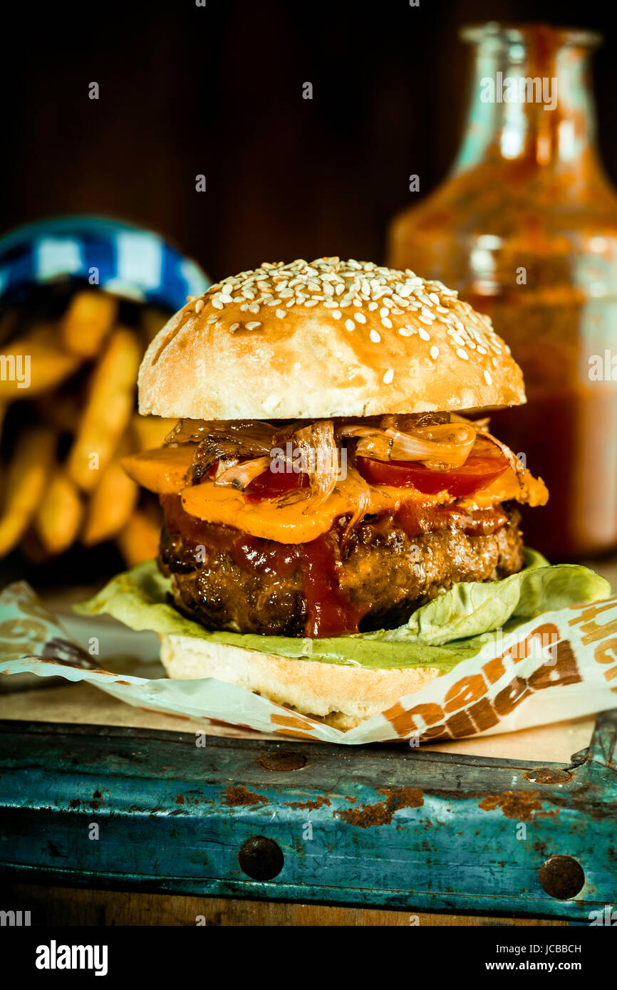 Macro acquolina in bocca a mano Burger Quarter Pounder con Frech Fries in stile rustico. Foto Stock