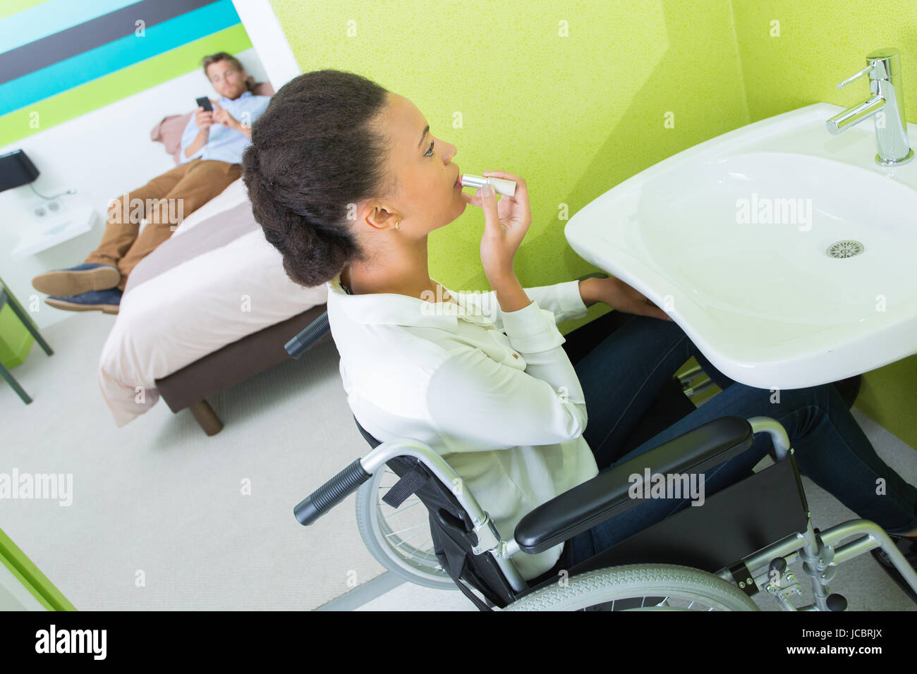 Una donna disabile mettendo sul trucco nella camera di albergo Foto Stock