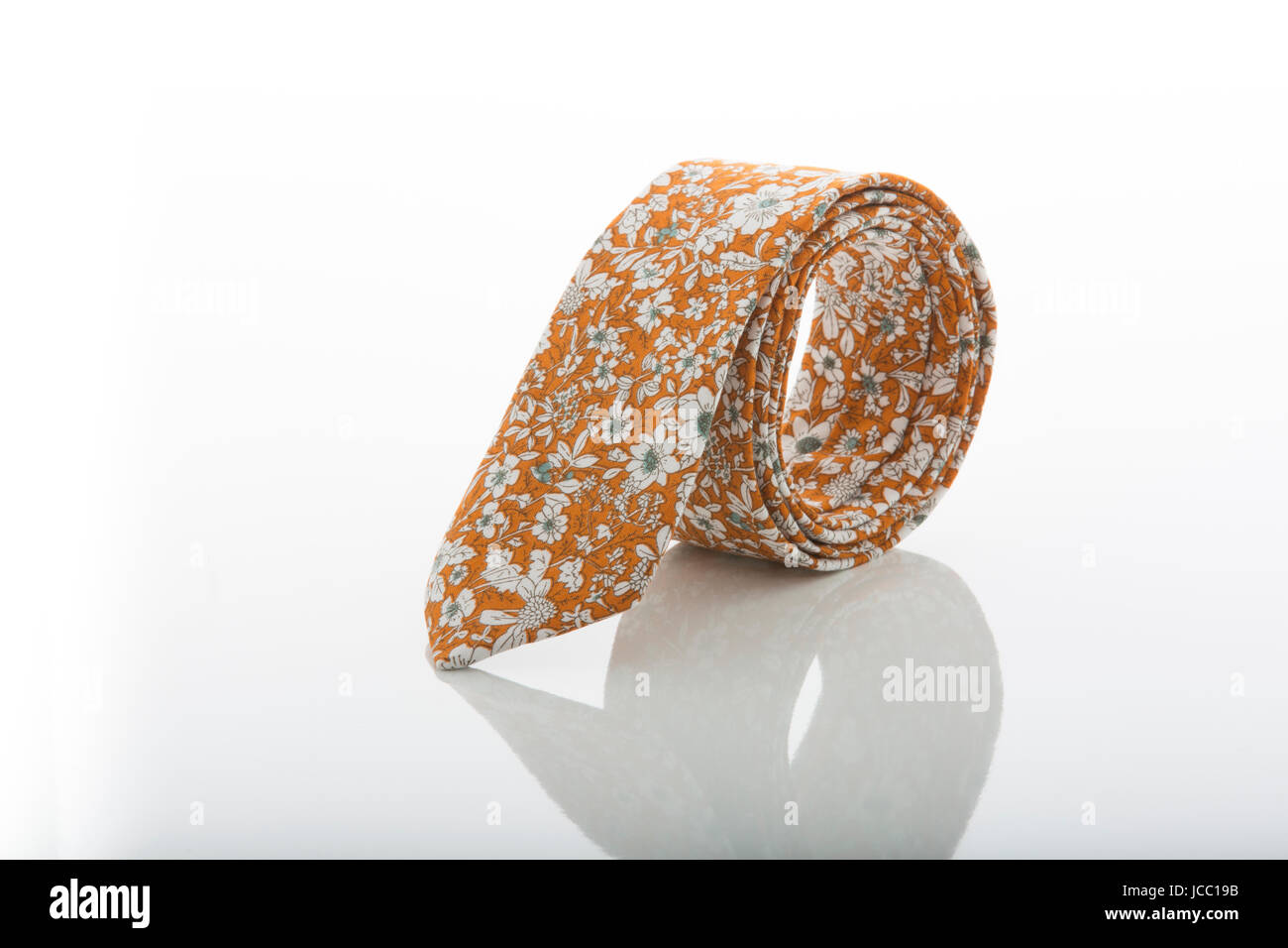 Tirante arrotolato in cerchio con una riflessione di fondo. Il colore dominante è di colore arancione e bianco con motivi floreali. Foto Stock
