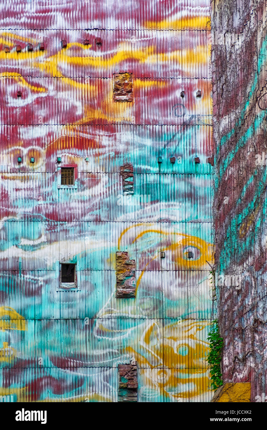 Un edificio esterno dipinto in vivaci e quasi psichedelica, colori fornisce uno sfondo luminoso per un vicolo di Barcellona. Foto Stock