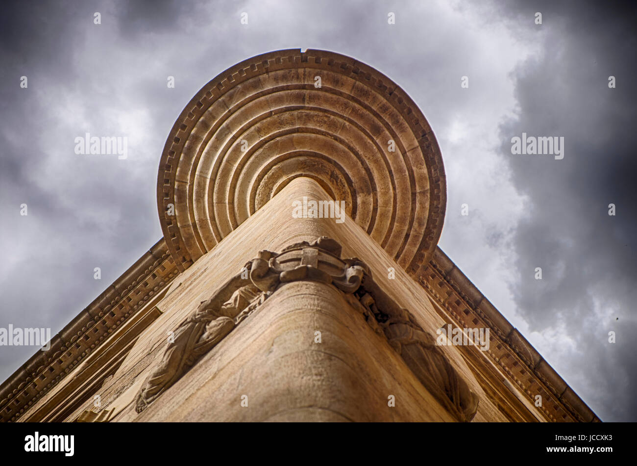 La parte inferiore di una torretta su un angolo della costruzione in Barcellona crea un modello geometrico con drammatico, molto nuvoloso sopra. Foto Stock