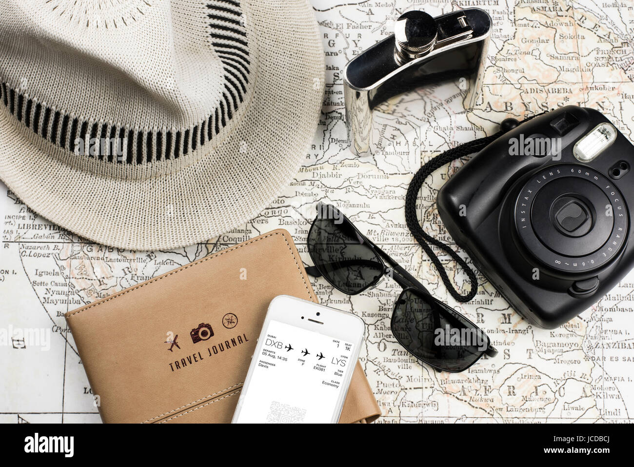 Elementi essenziali per il viaggio, un diario, una mappa antica, macchina fotografica istantanea, telefono con carta d'imbarco, occhiali da sole, matraccio e fedora, concetto di viaggio con tecnologia Foto Stock