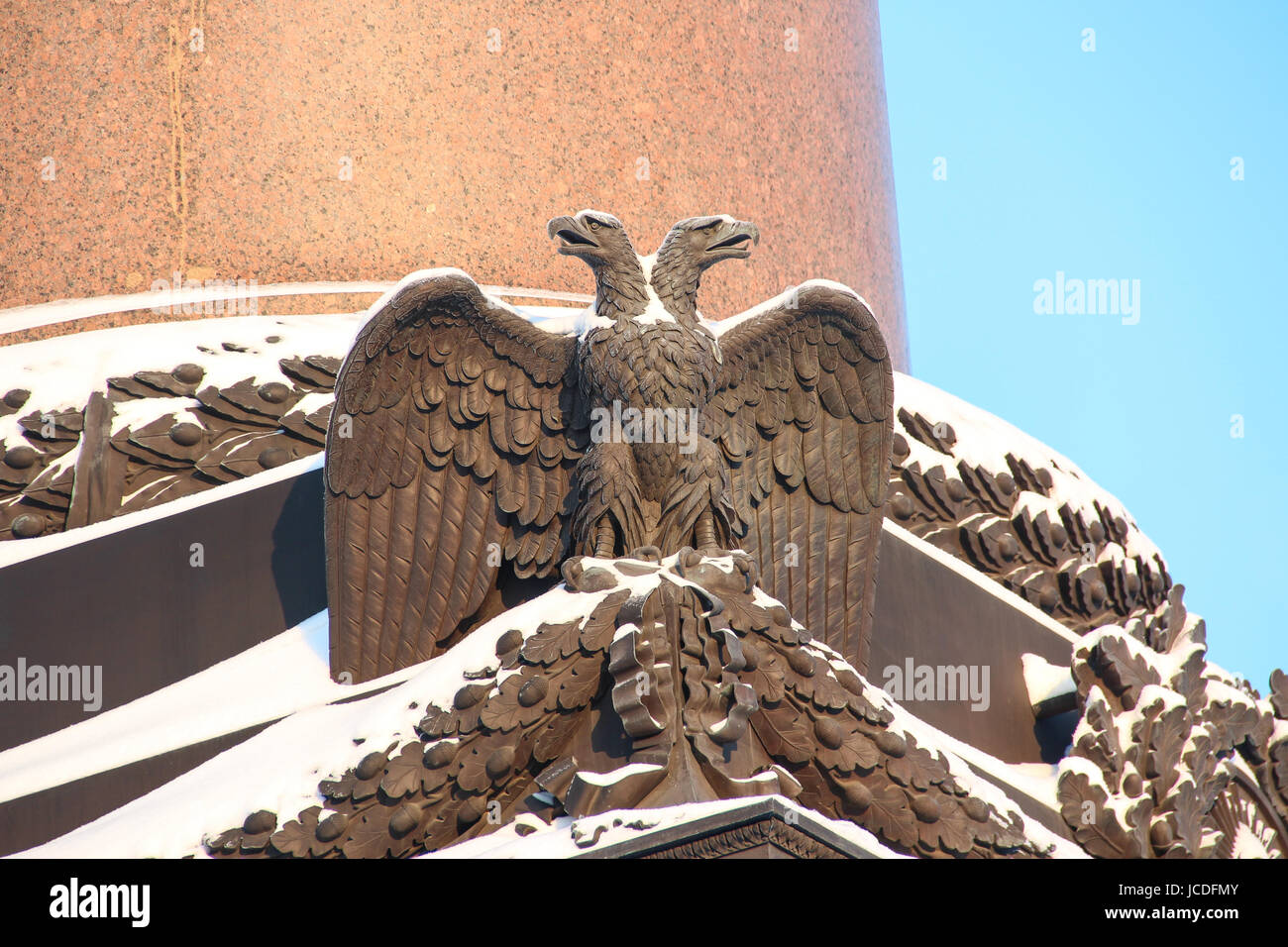Close up dettagli colonna Alexander decorazioni con imperiale russa di aquila a due teste simbolo ricoperta di neve sulla Piazza del Palazzo sullo sfondo Foto Stock