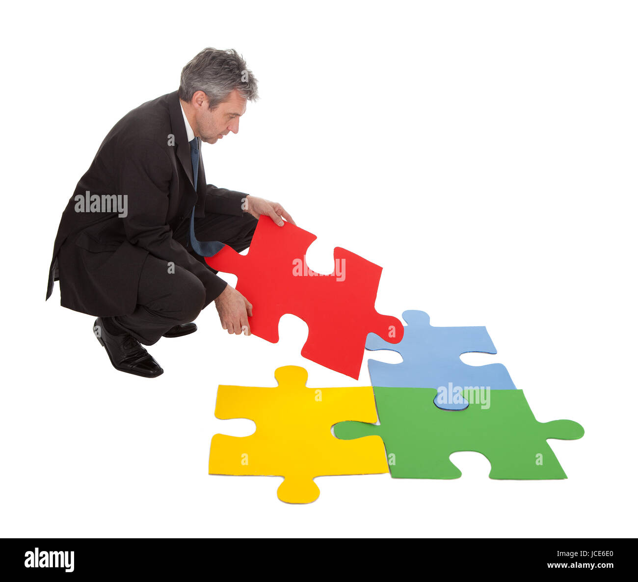 Imprenditore senior di assemblaggio di un puzzle. Isolato in bianco Foto Stock