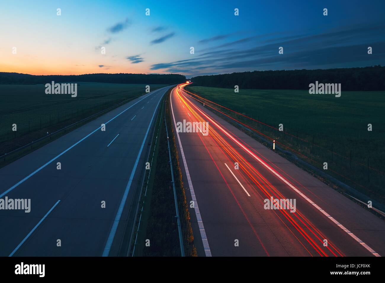 Luci di posizione posteriori delle vetture durante il sunrise sull'autostrada. Trasporto e vetture tema. Foto Stock