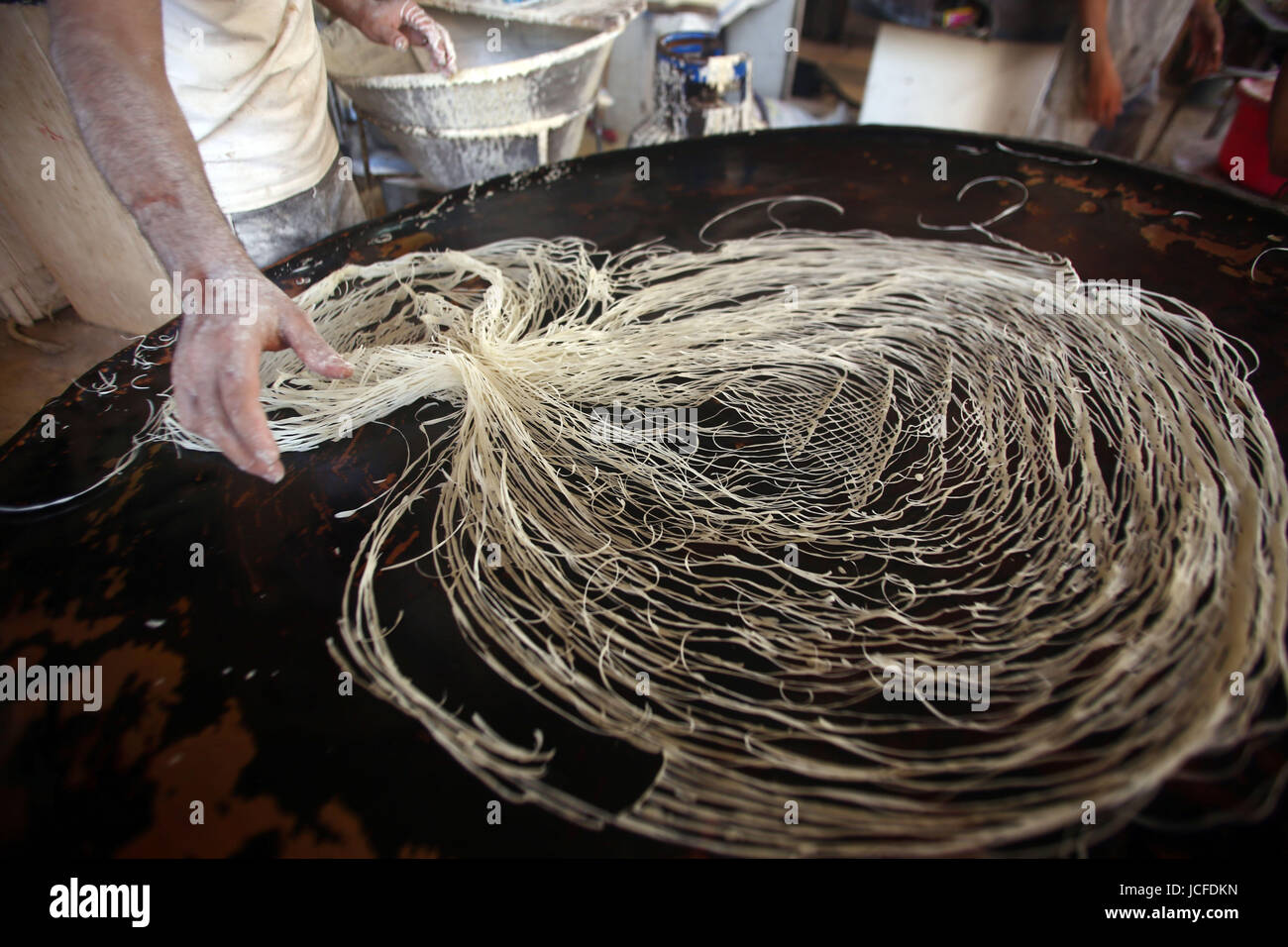 (170616) -- GIZA, 16 giugno 2017 (Xinhua) -- Un Egiziano baker rende kunafa, un tradizionale dessert egiziano, al di fuori di un grande negozio di pasticceria nel distretto di Faisal di dell'Egitto Giza provincia, 15 giugno 2017. Sopravvivere nei secoli, kunafa e qatayef sono realizzati in una miscela di farina, acqua, latte in polvere ed altri materiali. I clienti di età diverse, compresi gli uomini, le donne e i bambini, acquistare kunafa qatayef e cucinare prima del tramonto, la fine del digiuno di giorno e di godere di loro come dessert dopo il digiuno pasto noto tra i musulmani come iftar. (Xinhua/Ahmed Gomaa)(whw) Foto Stock