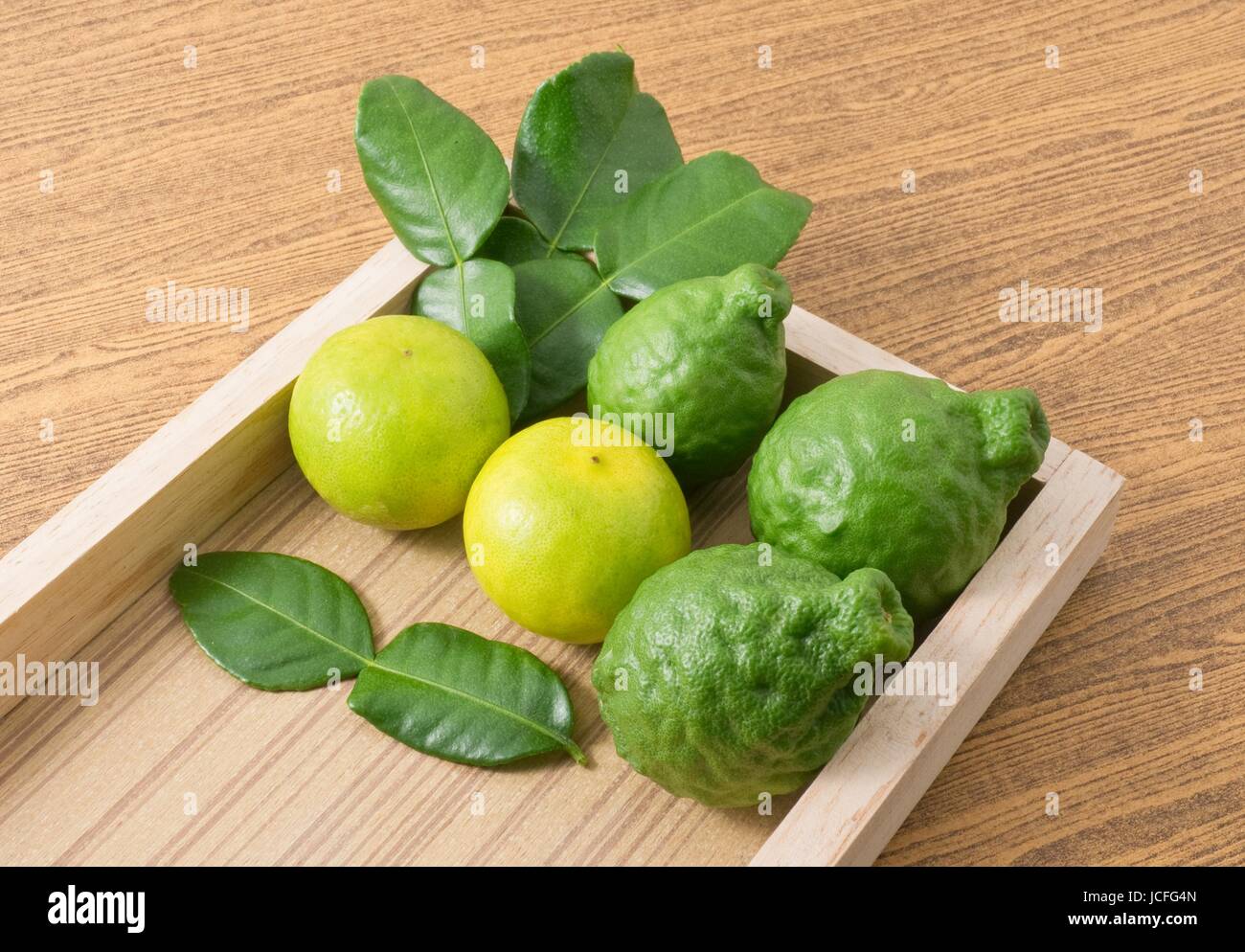 Vegetali e le erbe fresche di combava persiano con lime e foglie di Kaffir per la stagionatura in cottura su Vassoio in legno. Foto Stock