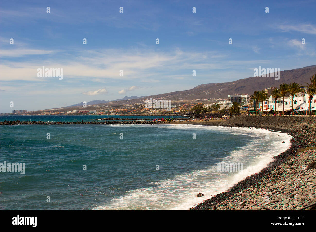 La soleggiata baia con il bianco di onde che si infrangono in spiaggia a Playa Las Americas in Teneriffe spagnole nelle isole Canarie Foto Stock