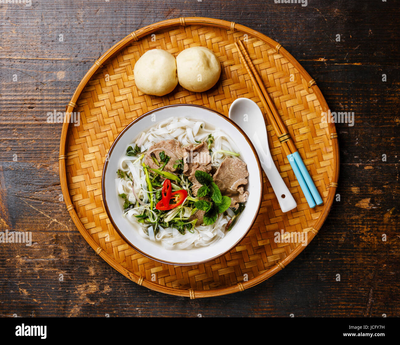 Pho Bo zuppa vietnamita con carne di manzo e di vapore bun Bao sul vassoio di bambù su sfondo di legno Foto Stock