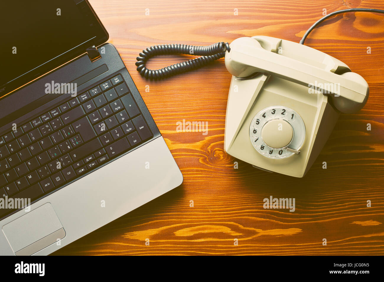 Telefono retrò e laptop moderno sul tavolo di legno Foto Stock
