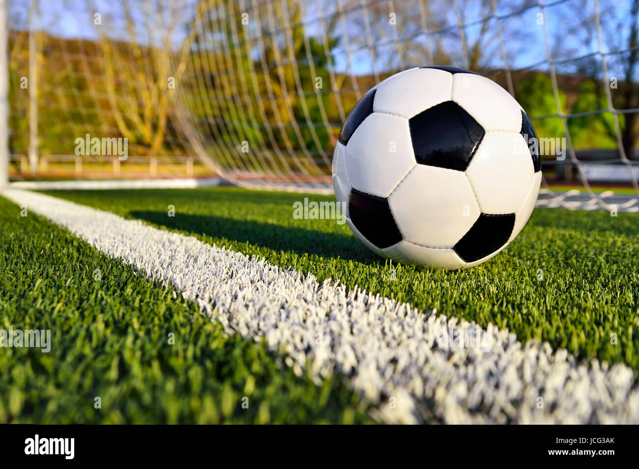 Fußball liegt auf einem sonnigen Fußballplatz hinter der Torlinie Foto Stock