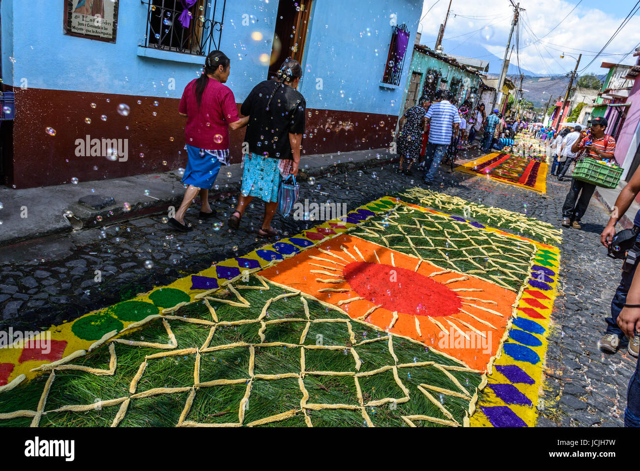 Antigua Guatemala - 6 marzo 2016: bubble venditore soffia bolle su segatura tinti & ago di pino quaresima tappeti per processione in città coloniale Foto Stock