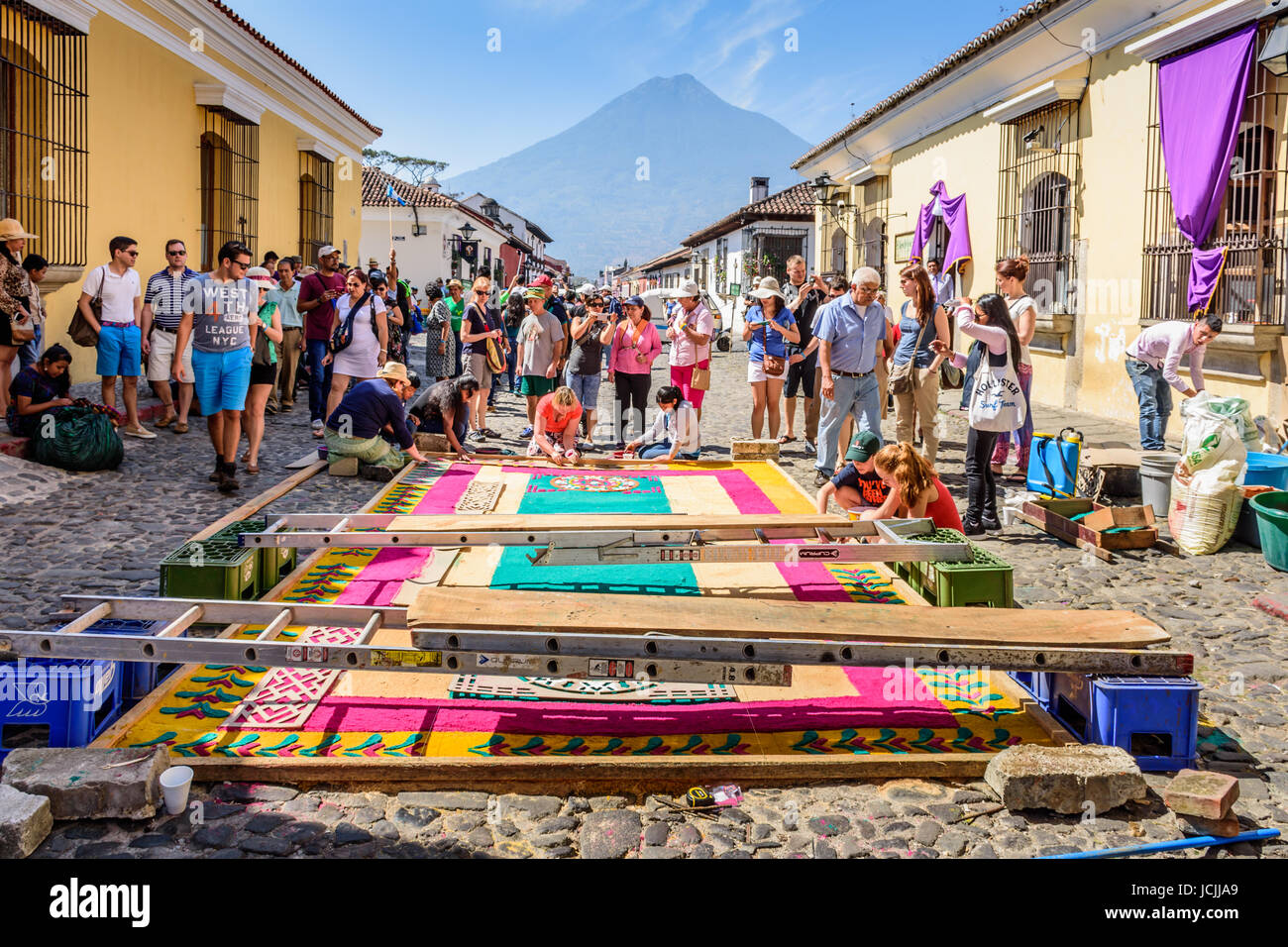 Antigua Guatemala - marzo 25, 2016: rendendo segatura colorata processione del venerdì santo di tappeti con agua vulcano in background Foto Stock