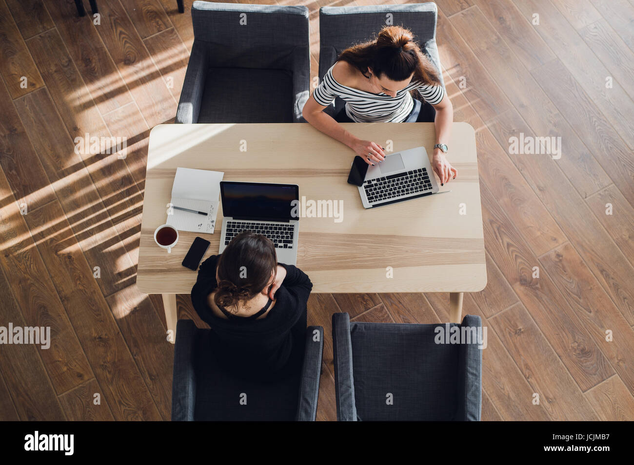 Startup business e nuova tecnologia mobile concetto con coppia giovane nella luminosa e moderna sede di lavoro interno sul laptop e tablet PC sul nuovo progetto creativo e di brainstorming, antenna vista dall'alto. Foto Stock