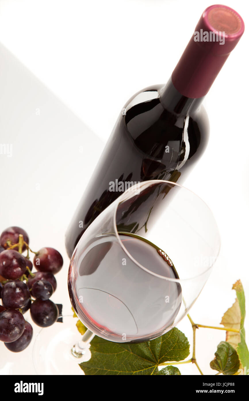 Rotwein im Glas mit Frucht, Blätter und Weinflasche Foto Stock