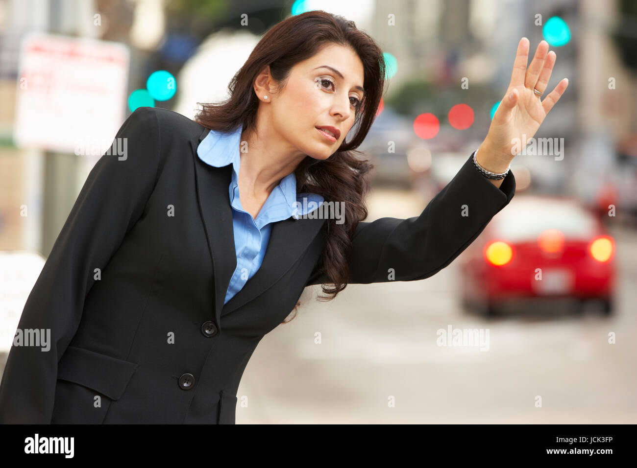 Imprenditrice salutando Taxi in strada trafficata Foto Stock