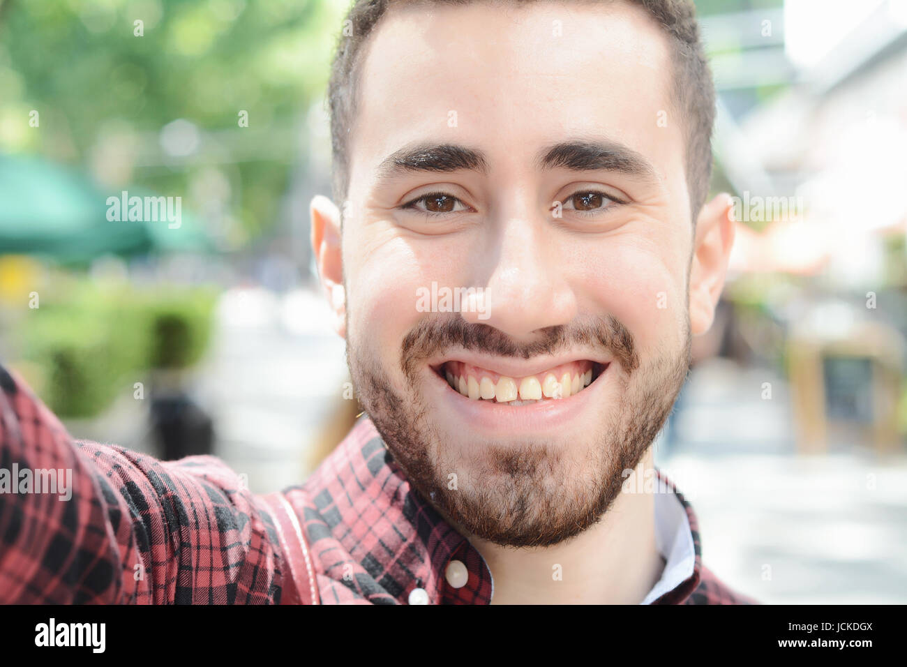 Giovane uomo latino tenendo un selfie. Scena urbana. All'esterno. Foto Stock