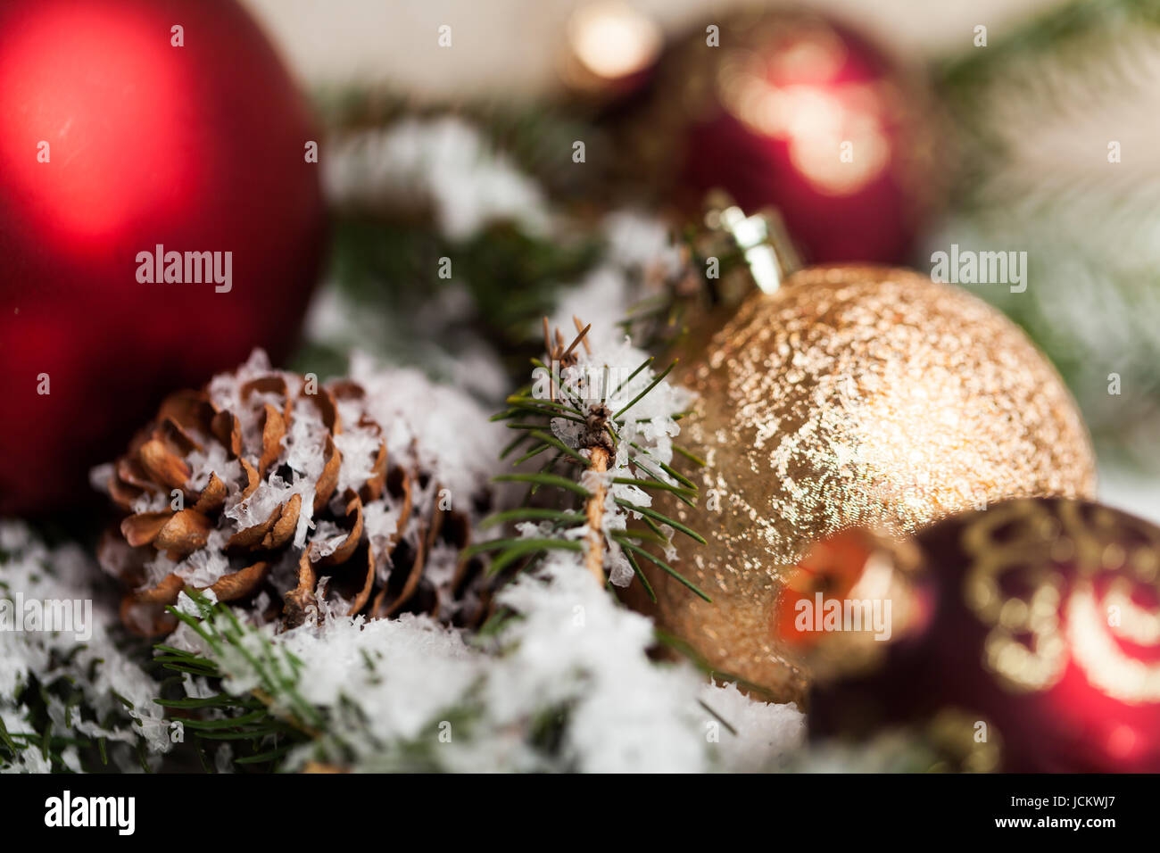 Rote Weihnachtskugeln zwischen Zapfen und Tannenzweigen mit Schnee bedeckt als dettaglio Macro Foto Stock