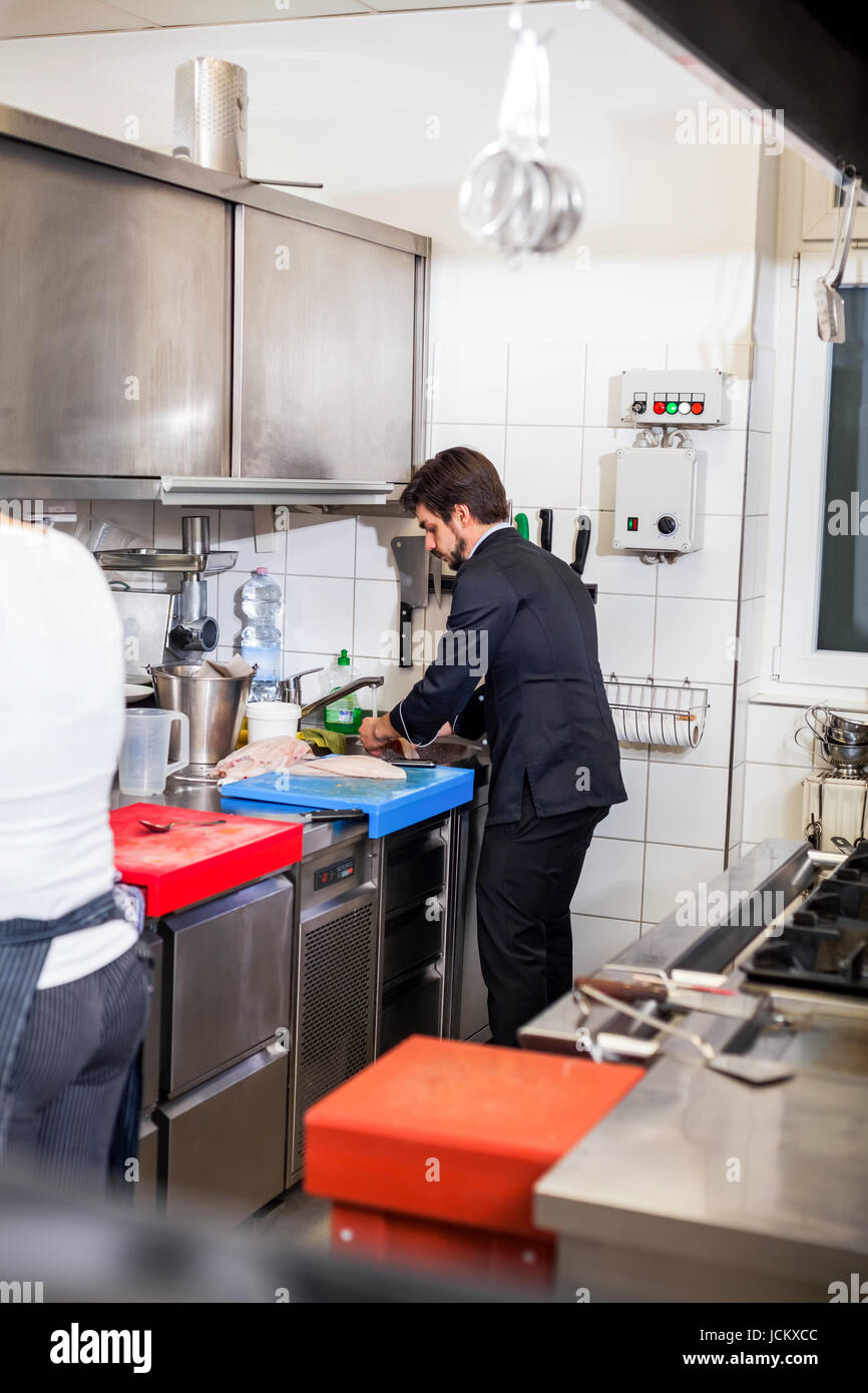 Junger erwachsener chefkoch in der ristorante küche beim kochen am zubereitung mandria Foto Stock