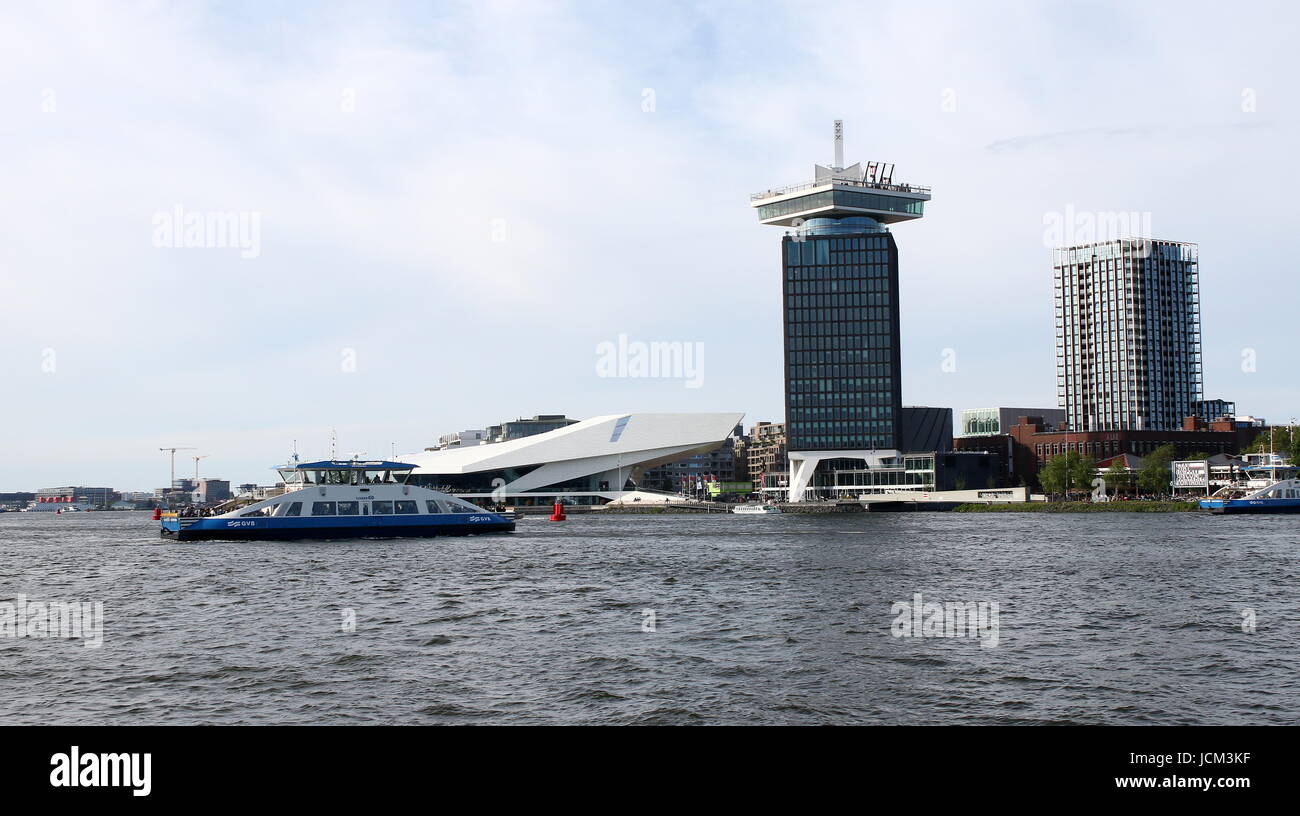 Pedone e bicicletta Ferry Crossing presso il fiume IJ dietro la stazione centrale di Amsterdam, Paesi Bassi. Occhio film museum e un'DAM torre in background Foto Stock