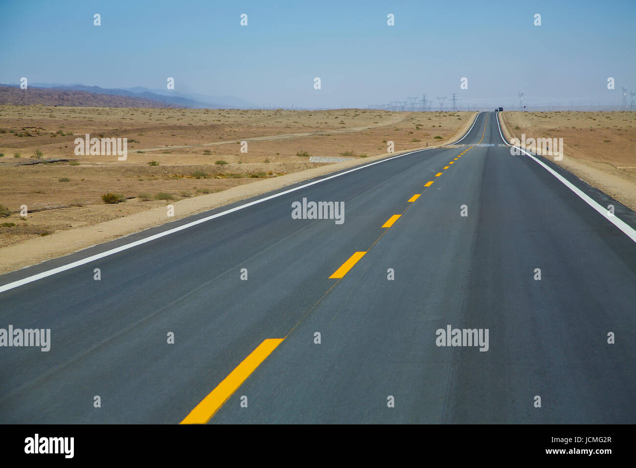 Vuoto lungo strada asfaltata nel deserto con cielo blu chiaro . Foto Stock