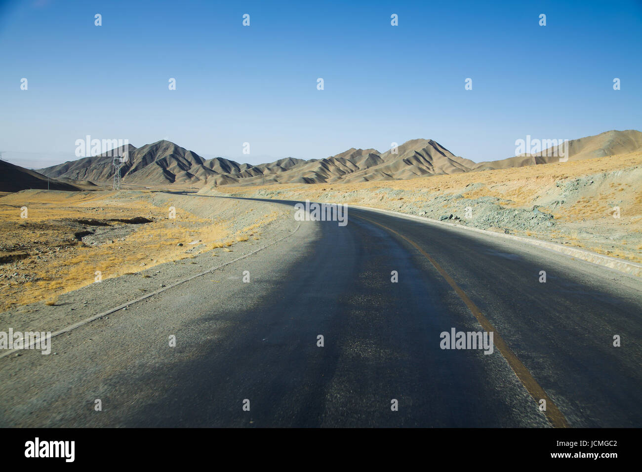 Lungo la curva vuota strada asfaltata nel deserto con cielo blu chiaro . Foto Stock