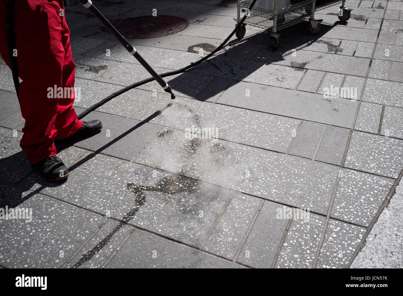 Uomo con la lancia vapore a pressione gomma pulito off sidewalkTimes Square di New York City STATI UNITI D'AMERICA Foto Stock