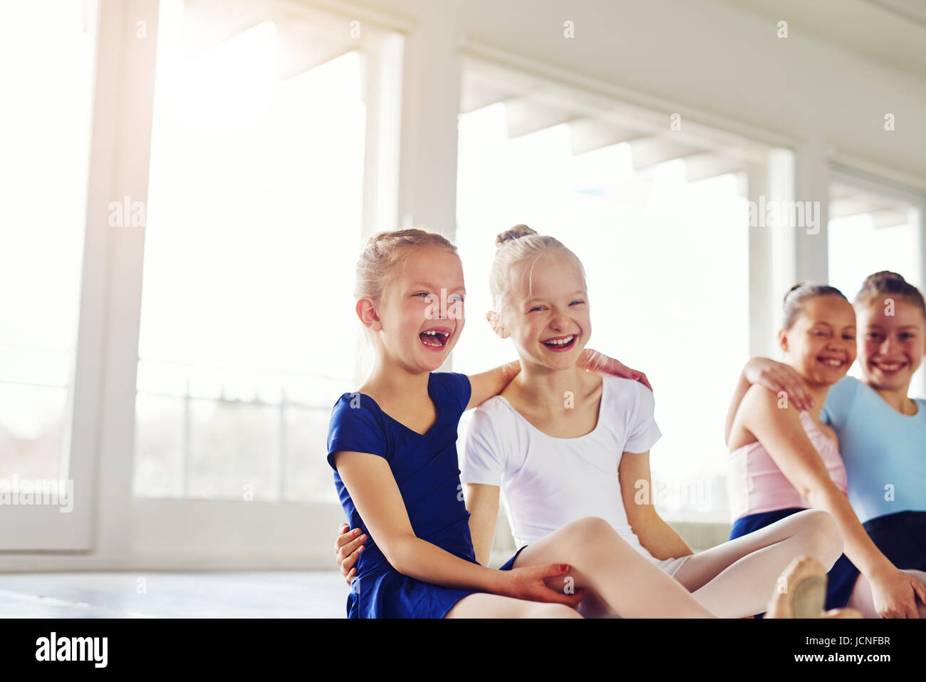 Carino bambine abbracciando e ridere seduto sul pavimento nella classe di balletto insieme. Foto Stock
