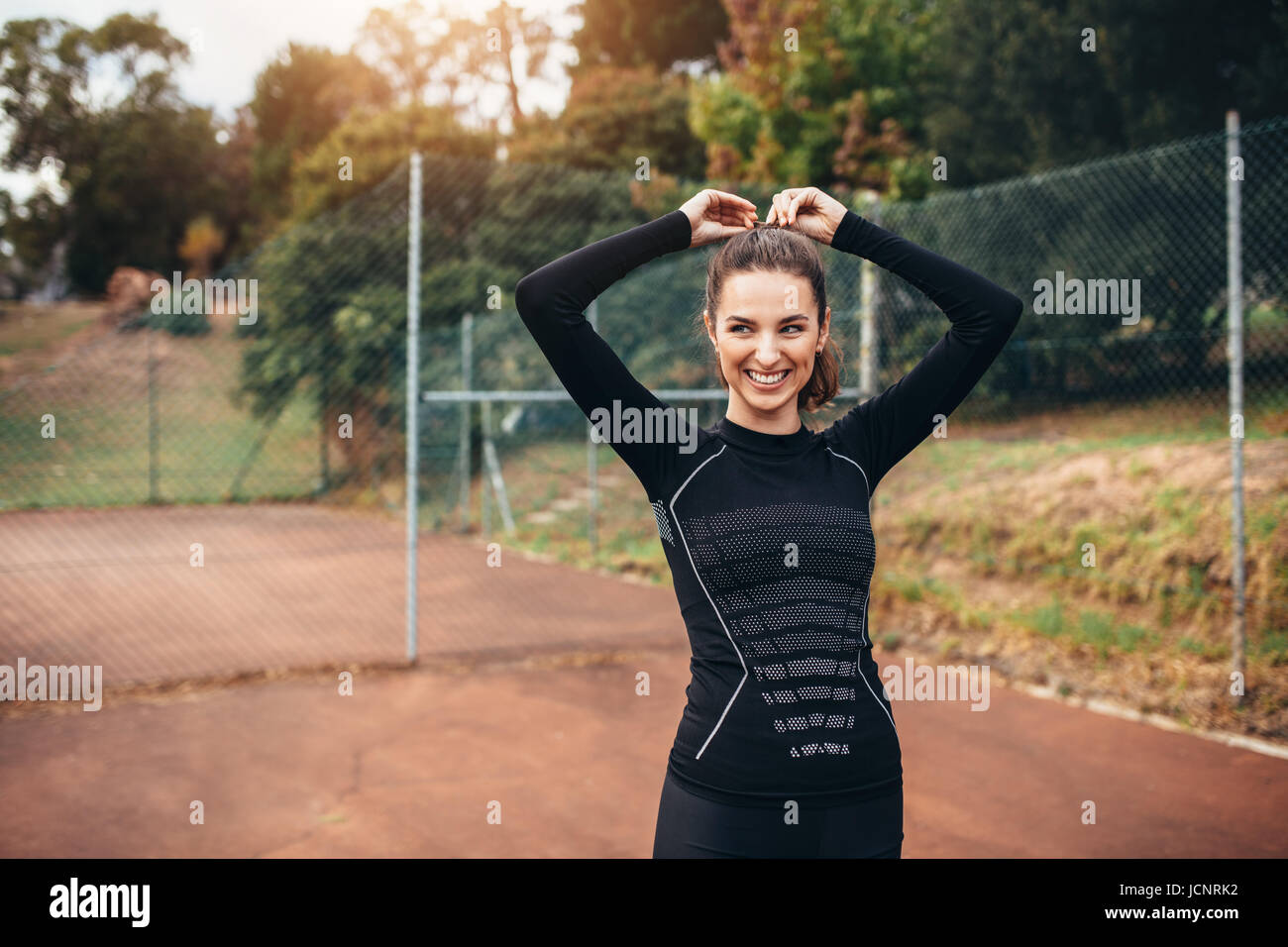 Ritratto di giovane sportivo donna sorridente all'esterno. Bella femmina fitness nell'abbigliamento sportivo che guarda lontano e sorridente. Foto Stock