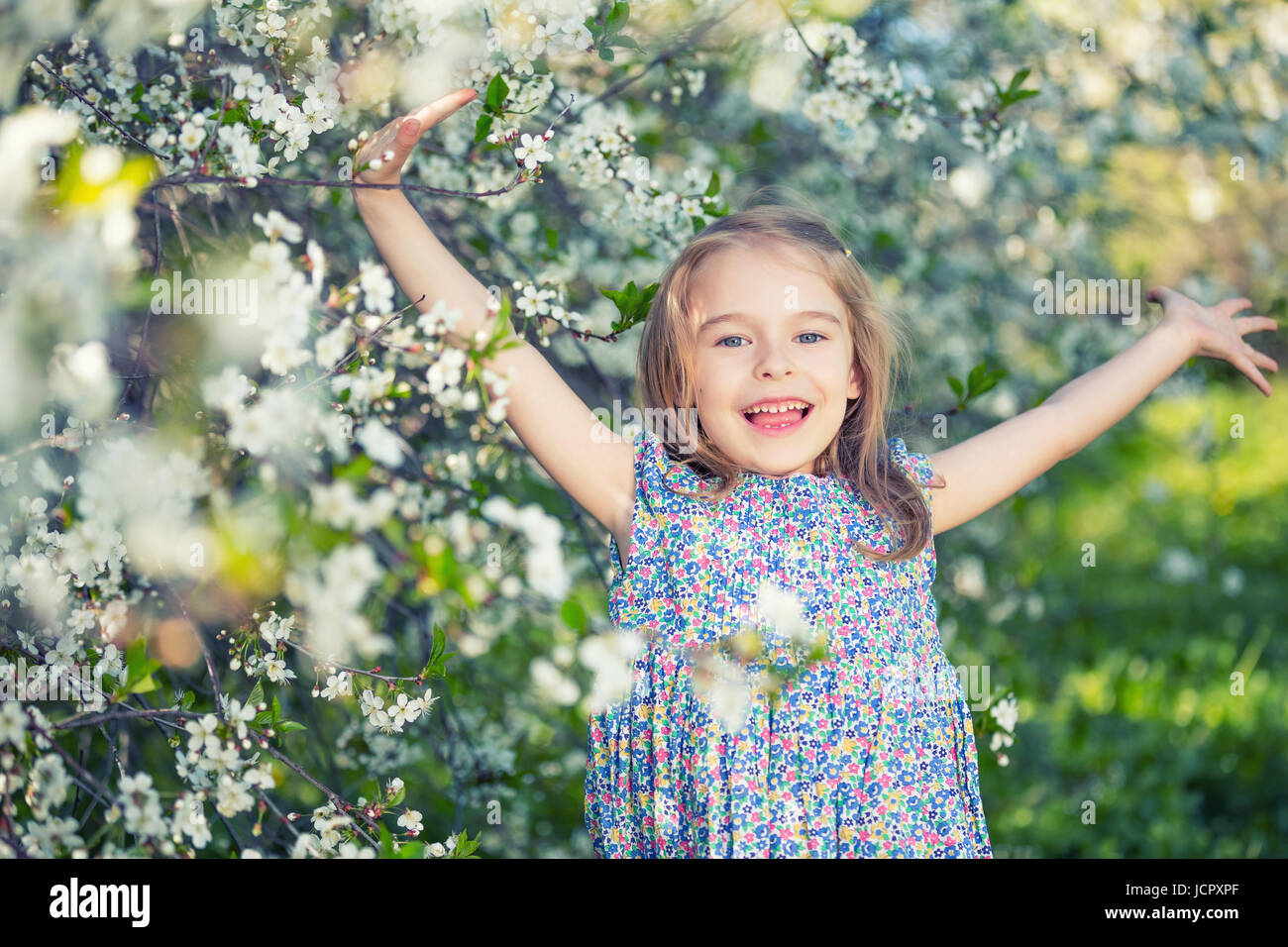 Felice bambina gioca nella primavera cherry garden Foto Stock