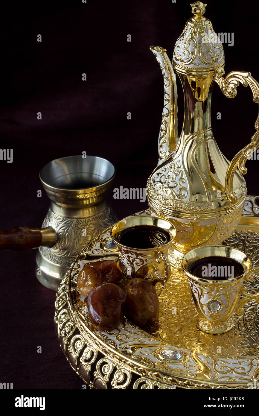 Ancora vita con tradizionale golden caffè arabo impostato con dallah, caffettiera e date. Sfondo scuro. Foto verticale. Foto Stock
