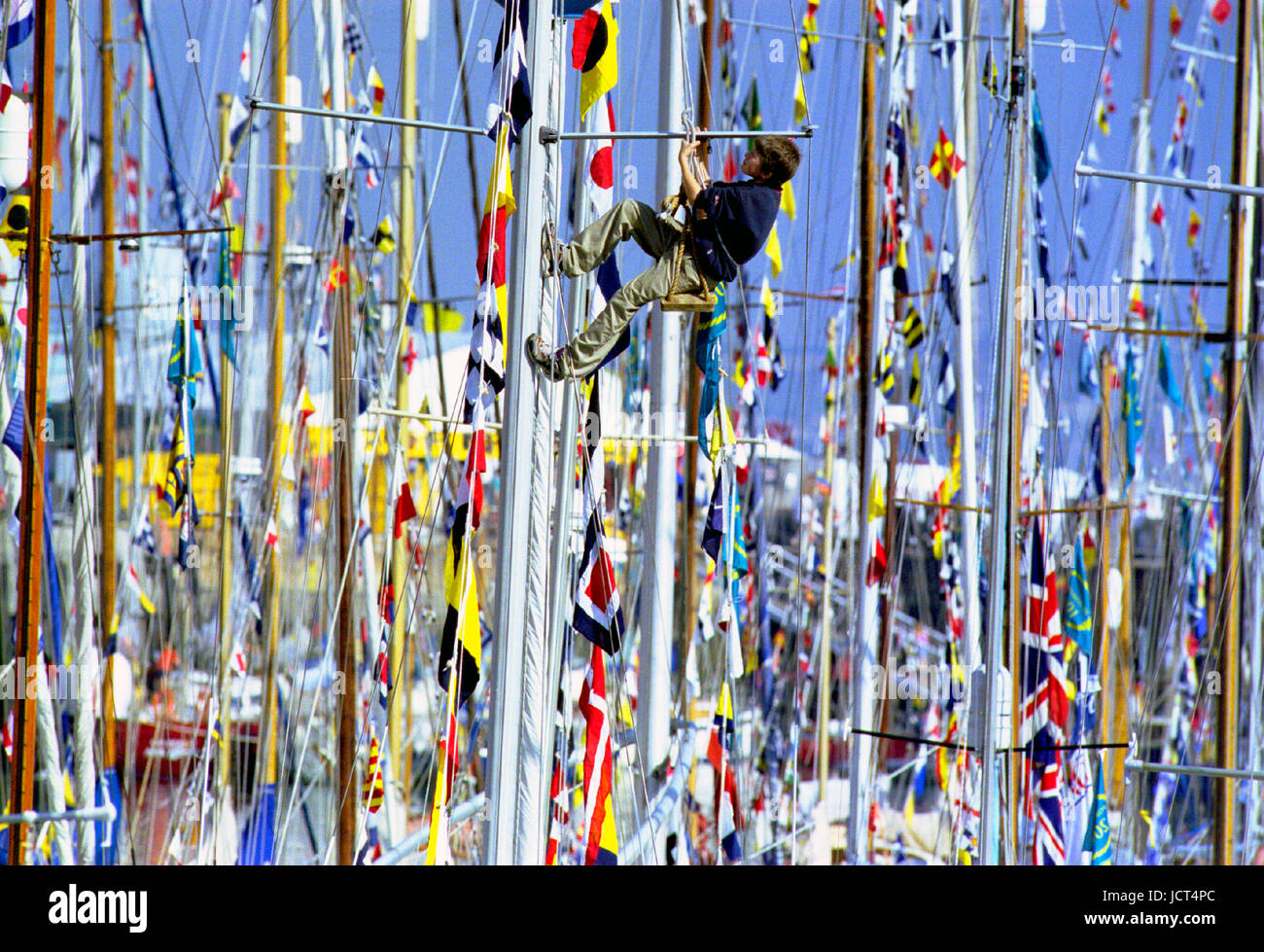 Il Festival internazionale del mare che coinvolge 1000 barche, era detenuto Portsmouth Naval Dockyard nel 2001. Un ragazzo in un bosun la sedia si arrampica su un montante. Foto Stock
