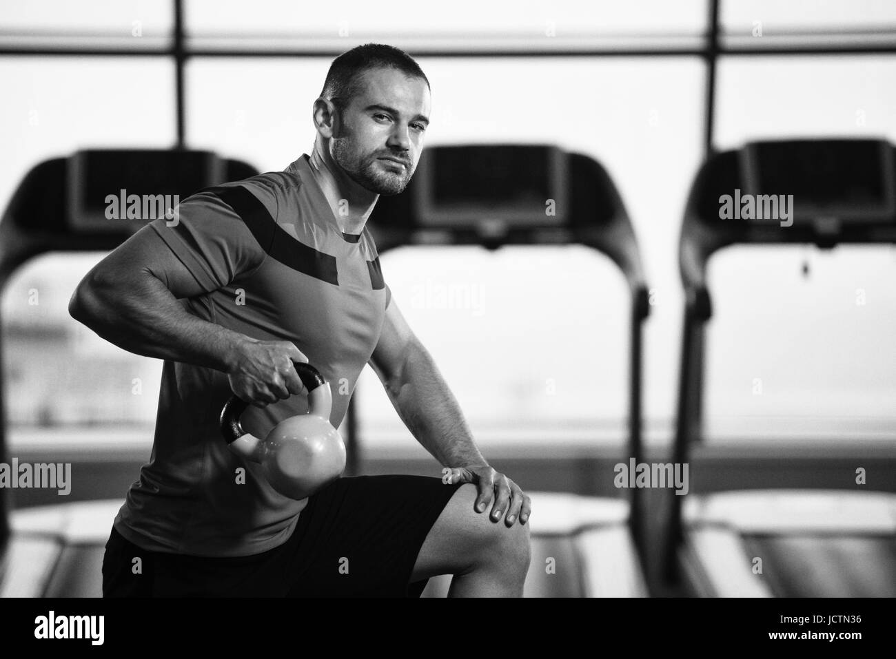 Giovane uomo fare esercizio con bollitore campana in palestra Foto Stock