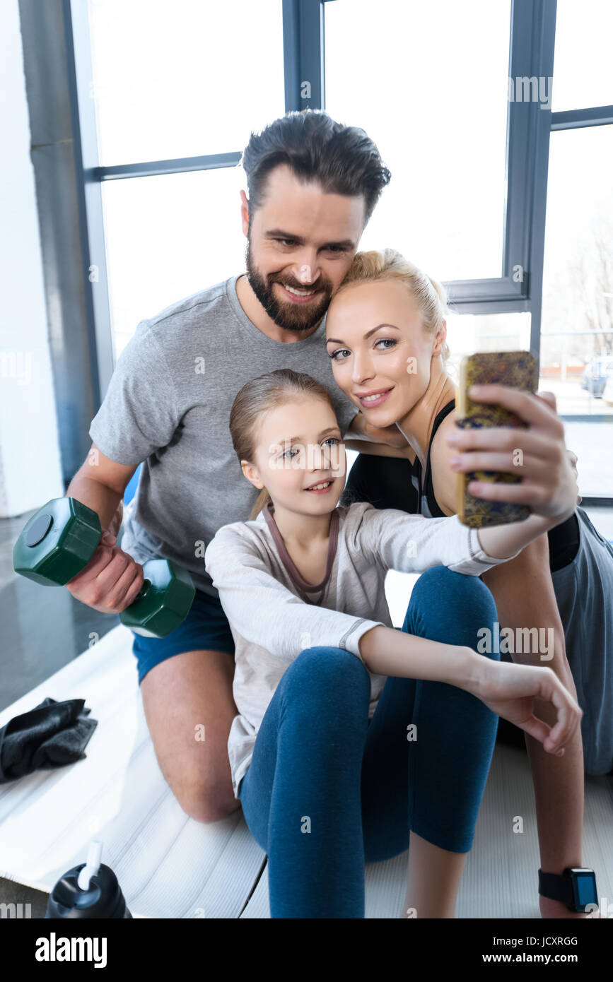 Ragazza tenendo autoritratto con i genitori al centro fitness Foto Stock
