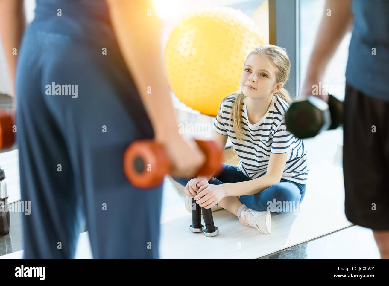 Persone Fitness esercizio con manubri mentre la ragazza seduta sul tappetino in studio fitness Foto Stock