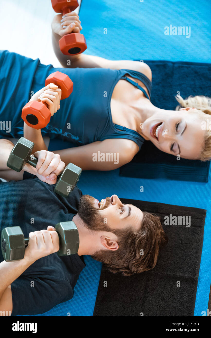 Coppia di giovani persone fitness esercizio con manubri in studio fitness Foto Stock