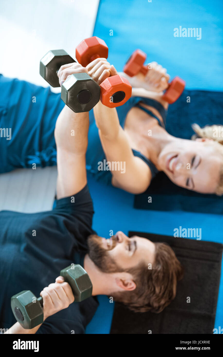 Coppia di giovani persone fitness esercizio con manubri in studio fitness Foto Stock