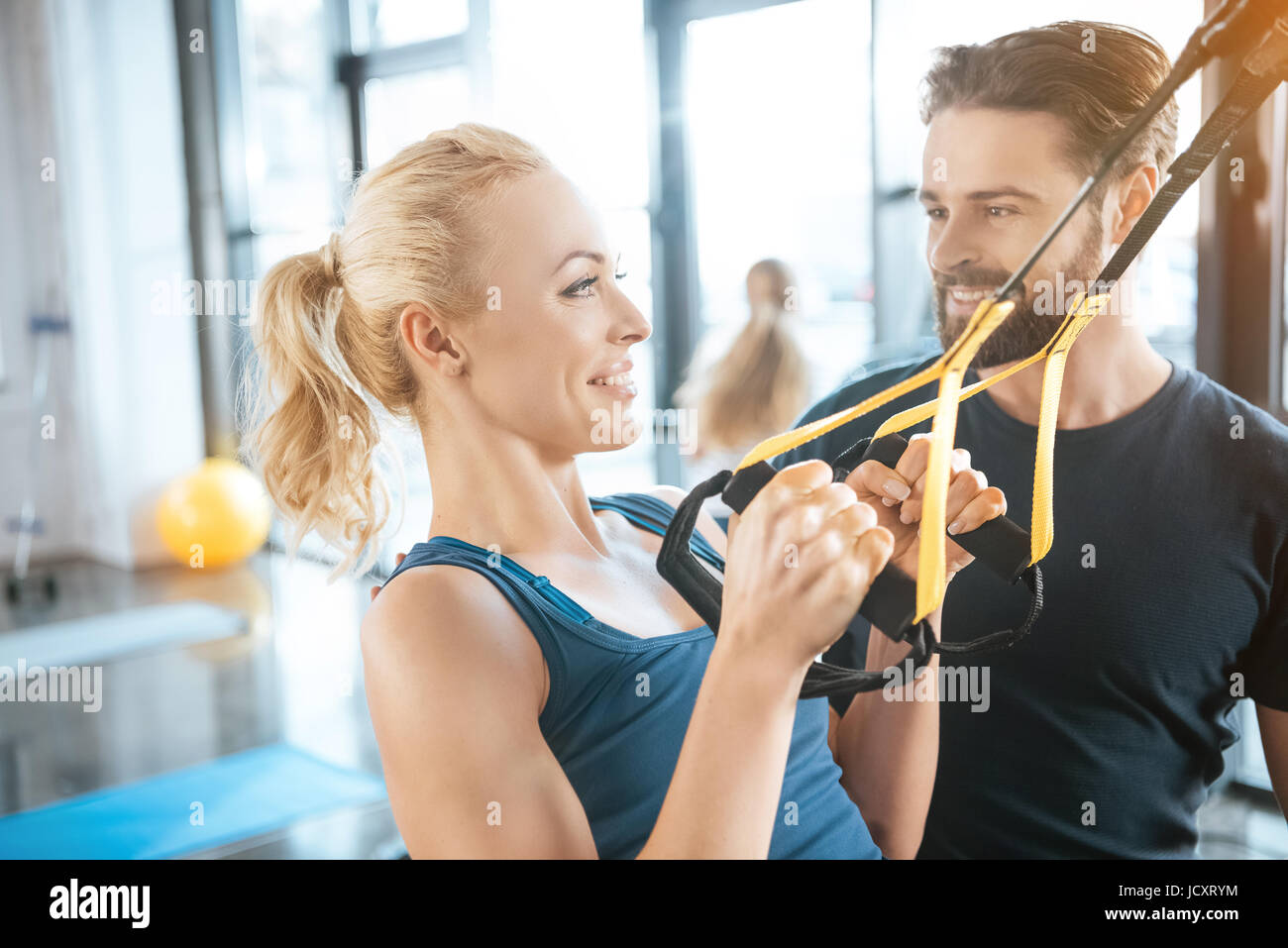 Pullman a parlare con la bionda donna fitness training con trx cinghie di fitness Foto Stock