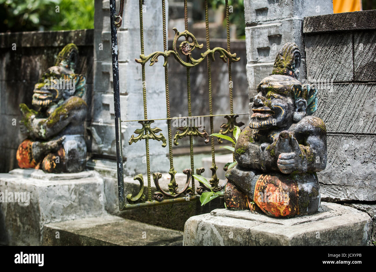 Statue in stile Balinese, unica effigie scolpita in pietra proteggendo l'ingresso di un tempio indù. Statue Balinese in la religione indù sono luogo comune Foto Stock