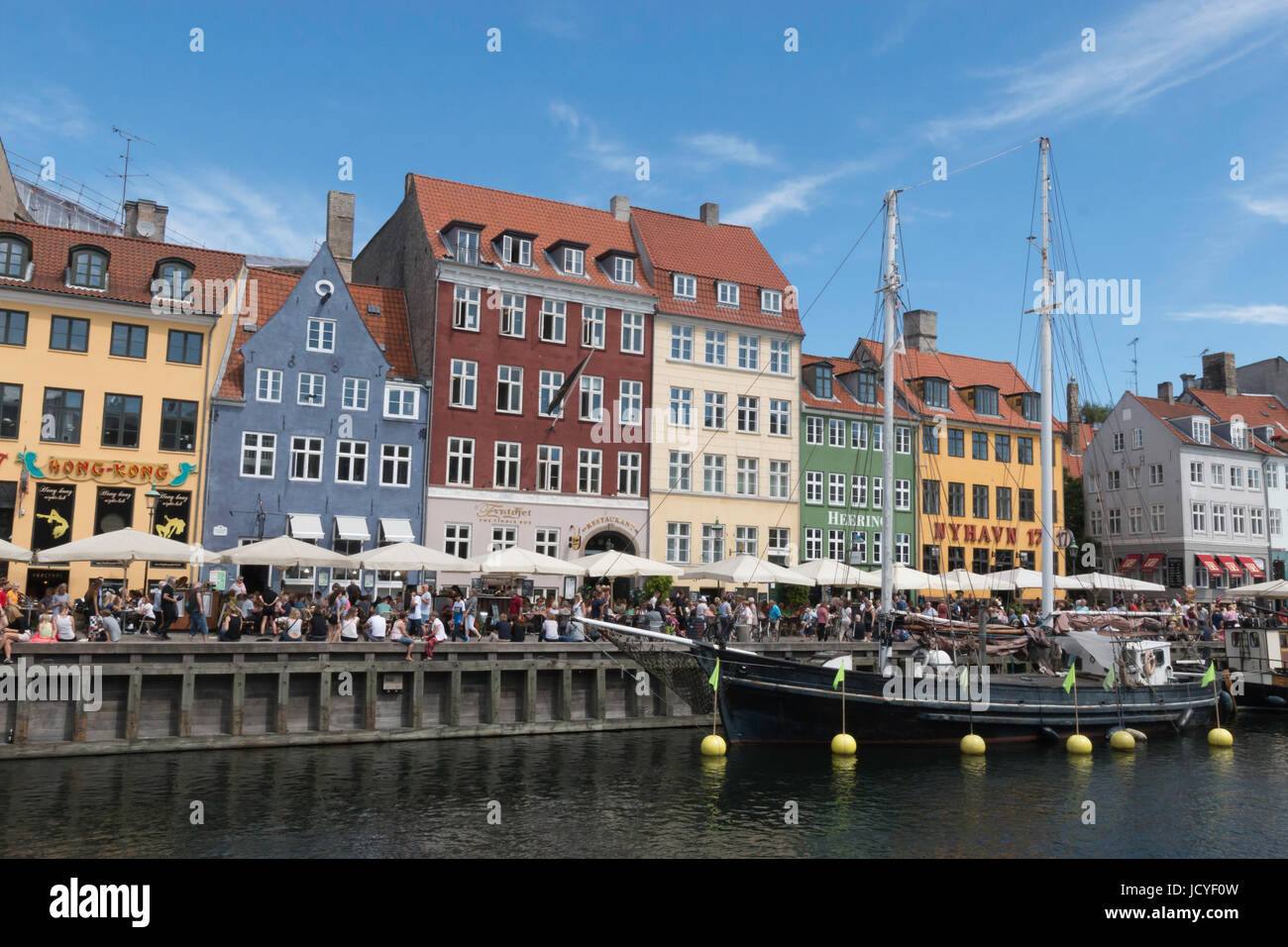 La folla folla sul lungomare a Nyhavn, Copenhagen su un luminoso giorno d'estate. una barca è ormeggiata sul canale. Foto Stock