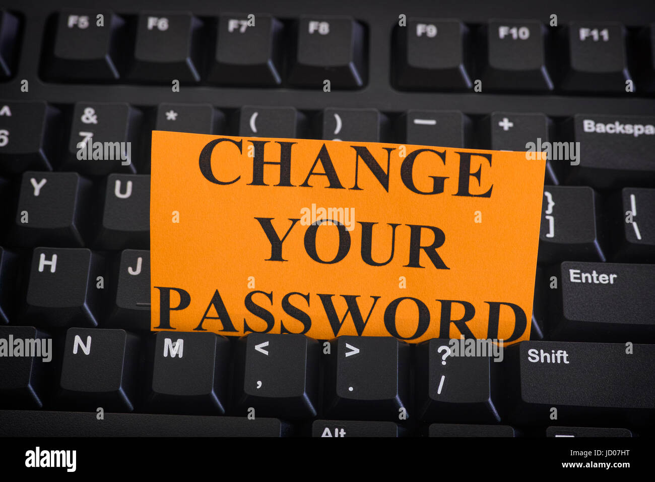 Nota di carta con la frase cambia la tua Password sul nero della tastiera del computer. Internet security concetto. Close up. Foto Stock