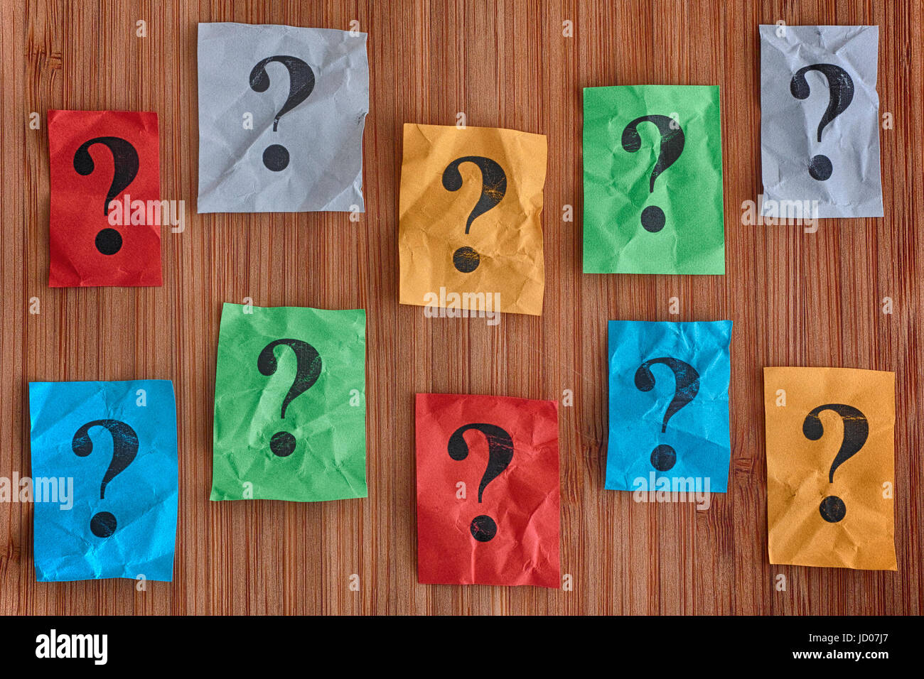 Carta colorata note con punti interrogativi su un sfondo di legno. Concetto di immagine. Foto Stock