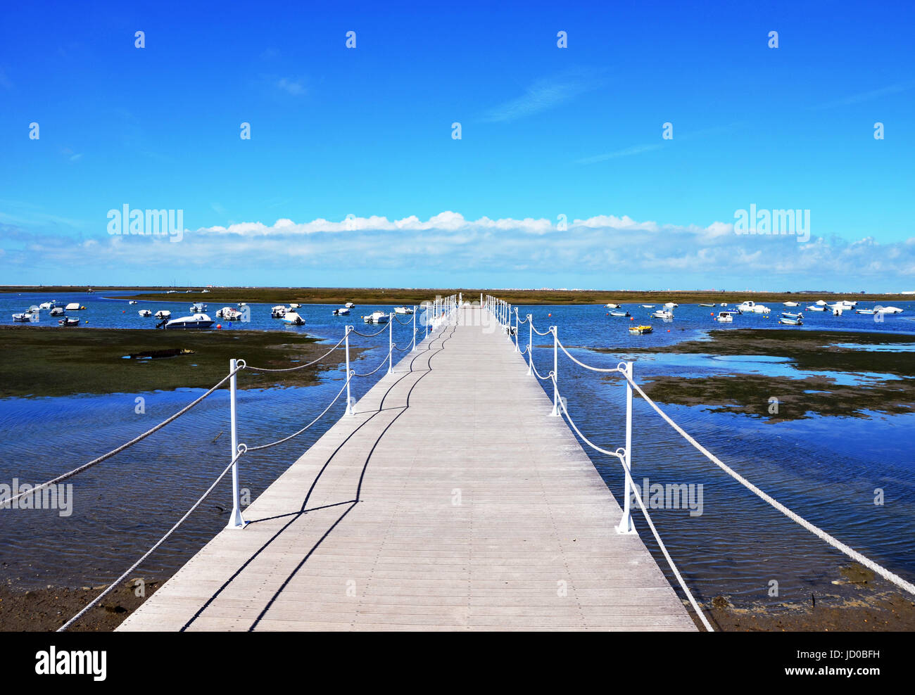 Porto di legno Jetty a Ria Formosa con cielo blu in background in Marina di Faro, Algarve, PORTOGALLO Foto Stock