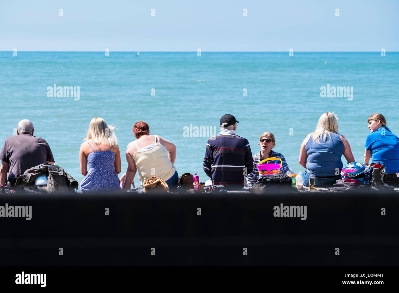 Aberystwyth, Wales, Regno Unito. 17 Giugno, 2017. Su di una splendida giornata di sole persone sedute sulla parete prom godendo della vista sul mare. Credito: Alan Hale/Alamy Live News Foto Stock