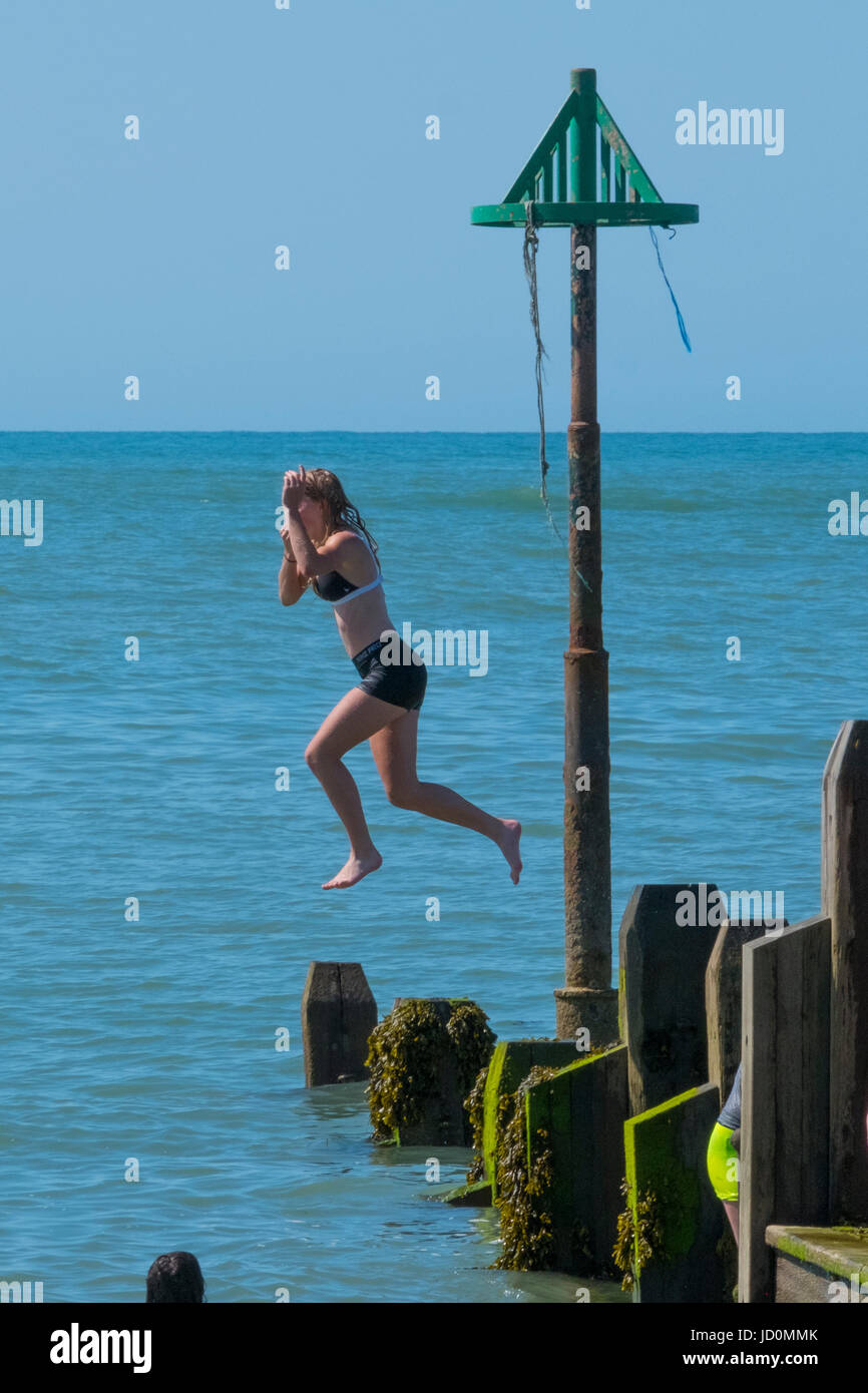 Aberystwyth, Wales, Regno Unito. 17 Giugno, 2017. In un ambiente caldo e meravigliosamente giornata soleggiata, giovani raffreddarsi saltando in mare dal rge pontile in legno. Credito: Alan Hale/Alamy Live News Foto Stock