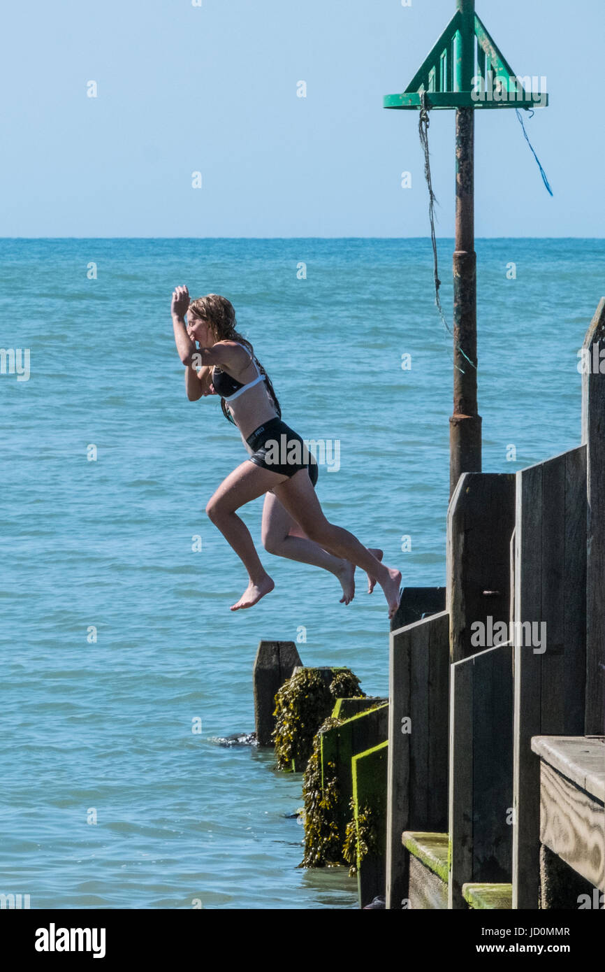 Aberystwyth, Wales, Regno Unito. 17 Giugno, 2017. In un ambiente caldo e meravigliosamente giornata soleggiata, giovani raffreddarsi saltando in mare dal rge pontile in legno. Credito: Alan Hale/Alamy Live News Foto Stock