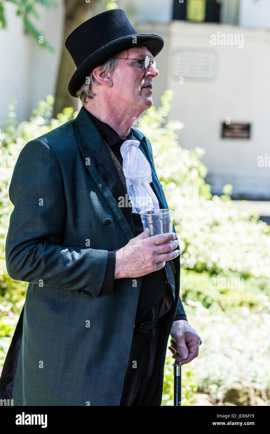 All'aperto, ritratto di uomo di mezza età, 40s, indossa una tuta steampunk e top hat con cravat. Tenuta del vetro di birra in mano. Vista laterale. Foto Stock