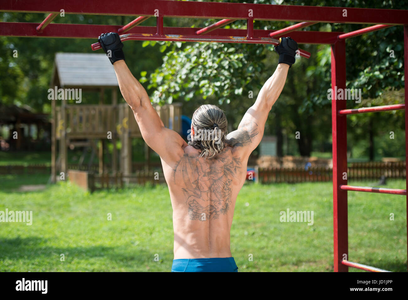 Costruito muscolare atleta che lavora fuori in una palestra a cielo aperto - facendo chin-ups Foto Stock