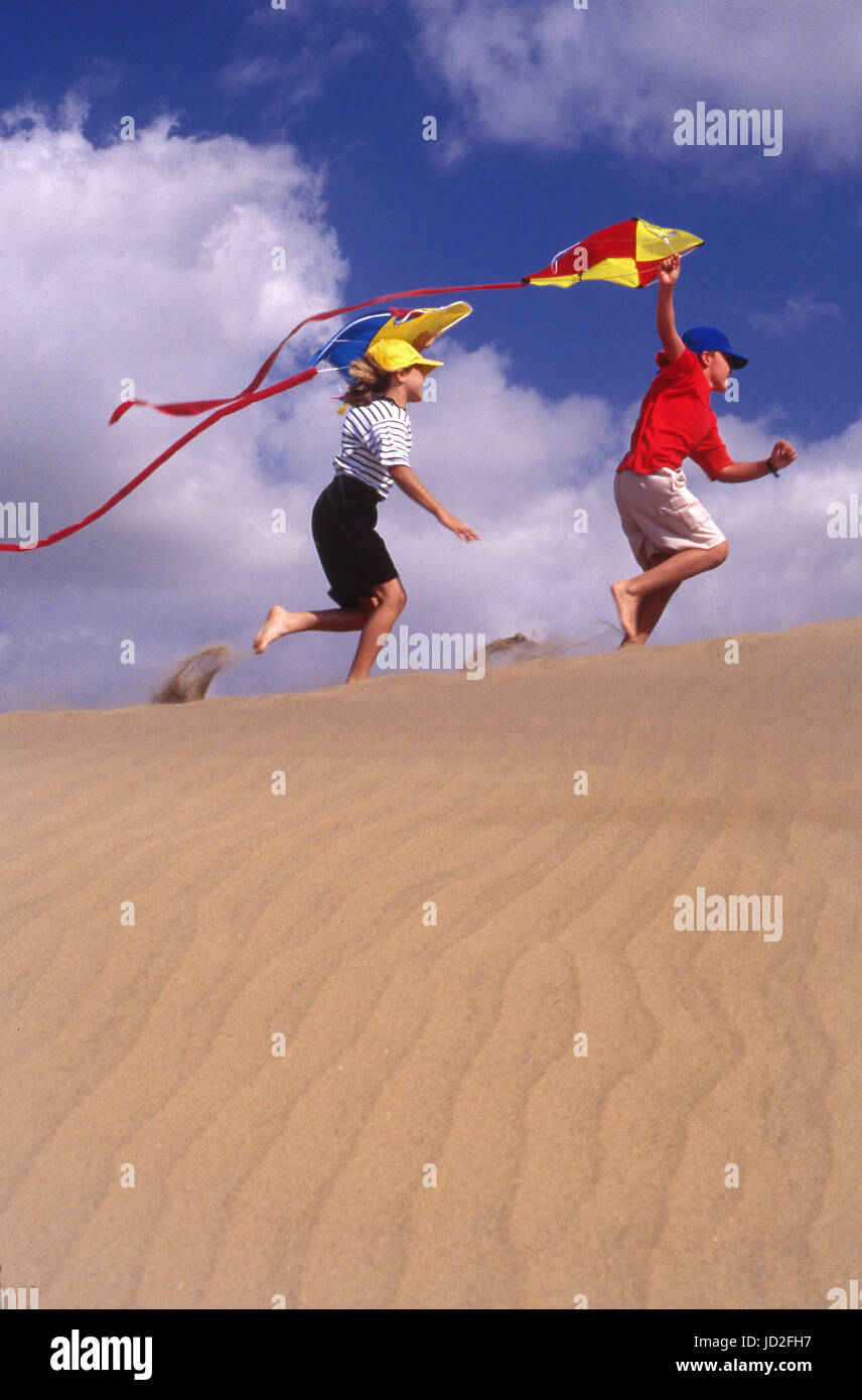 KITES DUNES DIVERTIMENTO PER TUTTA LA FAMIGLIA Boy and Girl 8-11 anni di corsa su dune di sabbia con kites colorati godendo della loro vacanza estiva attiva soleggiata KODAK Foto Stock